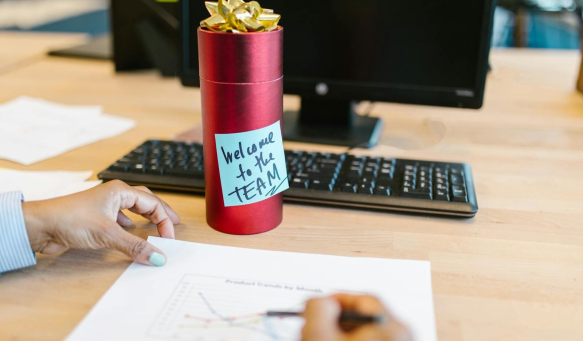 A welcoming gift on an office desk with a computer and person holding a chart.